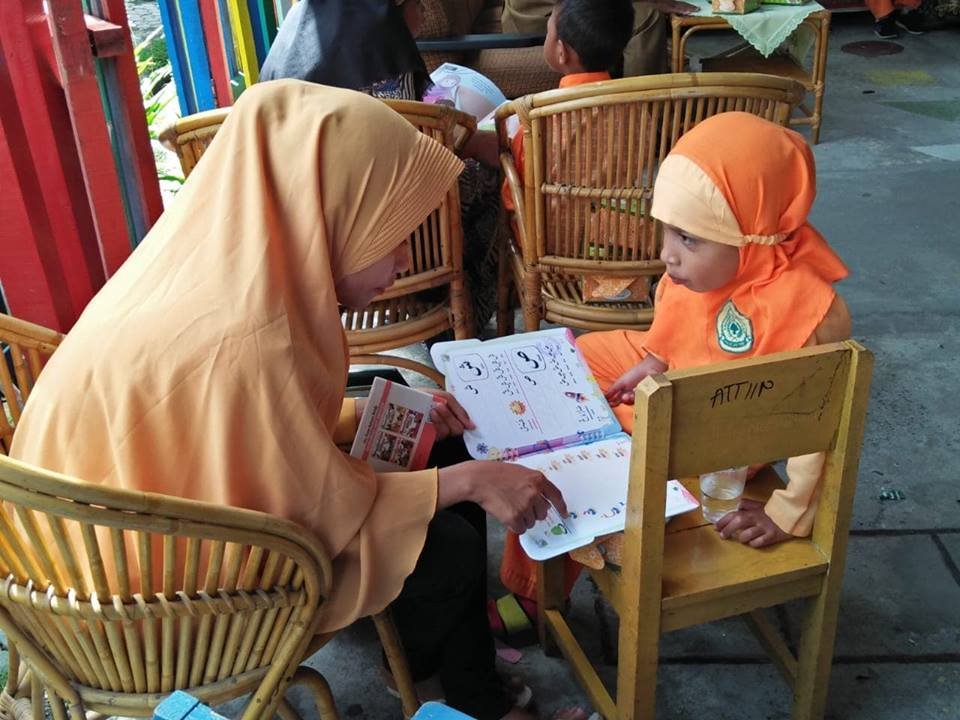 Seorang ibu (orang tua) sedang mendampingi anaknya mengajarkan dan memperkenalkan huruf dan gambar pada halaman-halaman buku, saat berlangsungnya kegiatan Literasi Keluarga di PAUD/TK-Atiin Masohi. 