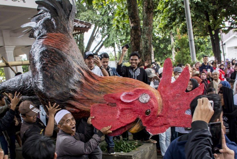 Warga membawa patung ayam yang merupakan simbol pemerintahan Cianjur saat aksi unjuk rasa terkait tertangkapnya bupati Cianjur di alun-alun, Kabupaten Cianjur, Jawa Barat, Jumat (14/12/2018). (Foto : Antara)