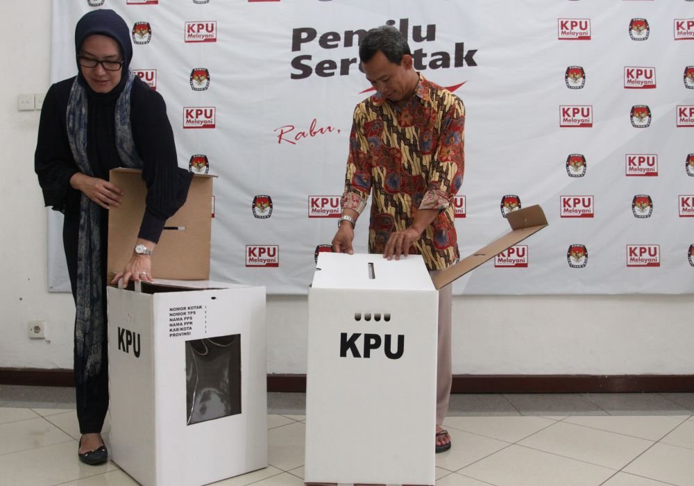 Komisioner Komisi Pemilihan Umum, Evi Novida Ginting Manik (kiri) dan Pramono Ubaid Tanthowi (kanan), menunjukan kotak suara bermaterial kardus di Kantor KPU Pusat di Jakarta, Jumat (14/12/2018). 