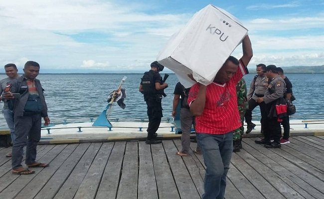 Seeorang petugas KPPS di Kabupaten Buru memikul kotak suara pasca berakhirnya pleno di PPK KecamatanTeluk Kayeli.  Seluruh logistik pemilu dibawa ke Namlea lewat laut dgn menggunakan speed boat. Kemudian dipindahkan ke kendaraan truk untuk dibawa ke kantor KPU, Sabtu (27/4/) (FOTO: BERITABETA.COM) 