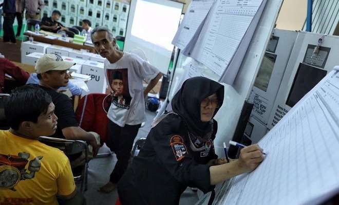 Ilustrasi : Seorang petugas KPPS yang menjalankan tugasnya dengan menulis hasil pemilihan di salah satu TPS