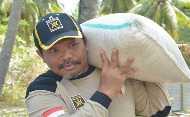 Johan Rosihan memanggul beras bantuan untuk korban gempa