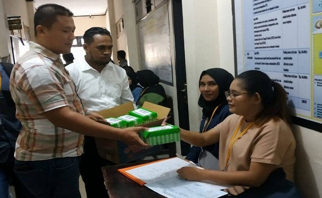 Seorang petugas di Mapolda Maluku tengah membagikan nasi kotak kepada sejumlah pemohon SKCK yang mengantri mengurus surat keterangan dari kepolisian untuk keperluan yang dibutuhkan, Senin (24/6/2019) (FOTO:BERITABETA.COM)