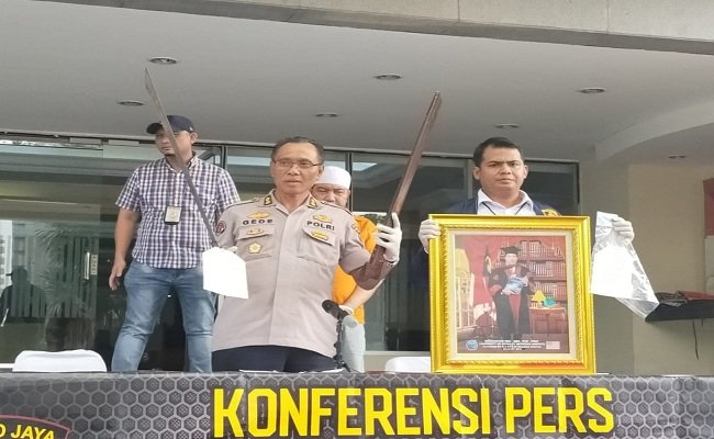 Kabid Penmas Humas Polda Metro Jaya AKBP I Gede Nyeneng memegang barang bukti senjata tajam milik Irwannur Latbual yang diamankan dan foto Irwannur Latbual yang menggunakan toga akademik dalam jumpa pers di Mapolda Metro Jaya, Selasa, (5/11/2019). (FOTO : BERITABETA.COM/DIP)