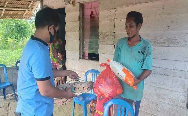 Bripka Abdul Majid saat mendatangi salah satu rumah di kawasan Kilo 12, Kelurahan Holo, Kecamatan Amahai, untuk membagikan paket sembako. Tampak Majid (baju biru) menyerahkan bantuan kepada salah satu warga di yang dijumpai di rumahnya, Kamis (28/5/2020).  