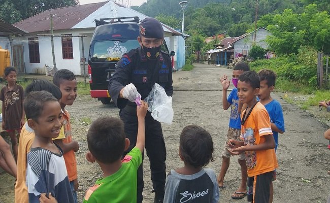 Personil Brimob Polda Maluku membagi-bagi masker kepada masyarakat di Ambon termasuk kepada anak-anak sebagai wujud dalam membantu pemerintah menekan turunnya angka positif corona. (Foto: Istimewa)