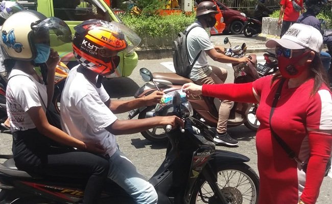 Salah seorang anggota Komunitas Maluku Satu Rasa Salam Sarane Bersatu (M1R – SSB) membagikan masker kepada pengendara kendaraan roda dua, di salah satu ruas jalan di Kota Ambon, Senin (26/10/2020)