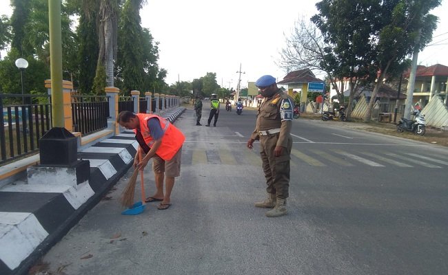 Salah satu warga Kota Namlea yang terjaring operasi yustisi dikenai sanksi menyapu jalanan oleh tim gabungan TNI-Polri Satpol PP, Senin (26/10/2020) (Foto : Istimewa)