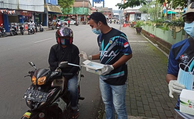 Anggota Komunitas RX King Kota Ambon saat membagikan masker kepada pengguna jalan di kawasan Gong Perdamaian Kota Ambon, Jumat (18/12/2020)