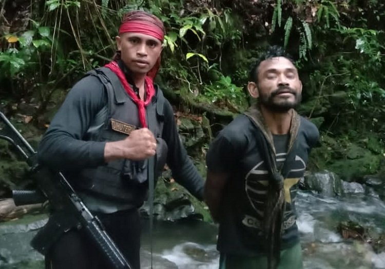 Salah satu anggota polisi saat mengiring Mantimbang Nurlatu pelaku pembunuhan Manpapa Latbual, usai ditangkap di tempat persembunyianya di Hutan Rodi, Pulau Buru, sekitar pukul 16.00 WIT, Sabtu (20/03/2021) (Foto : Istimewa)