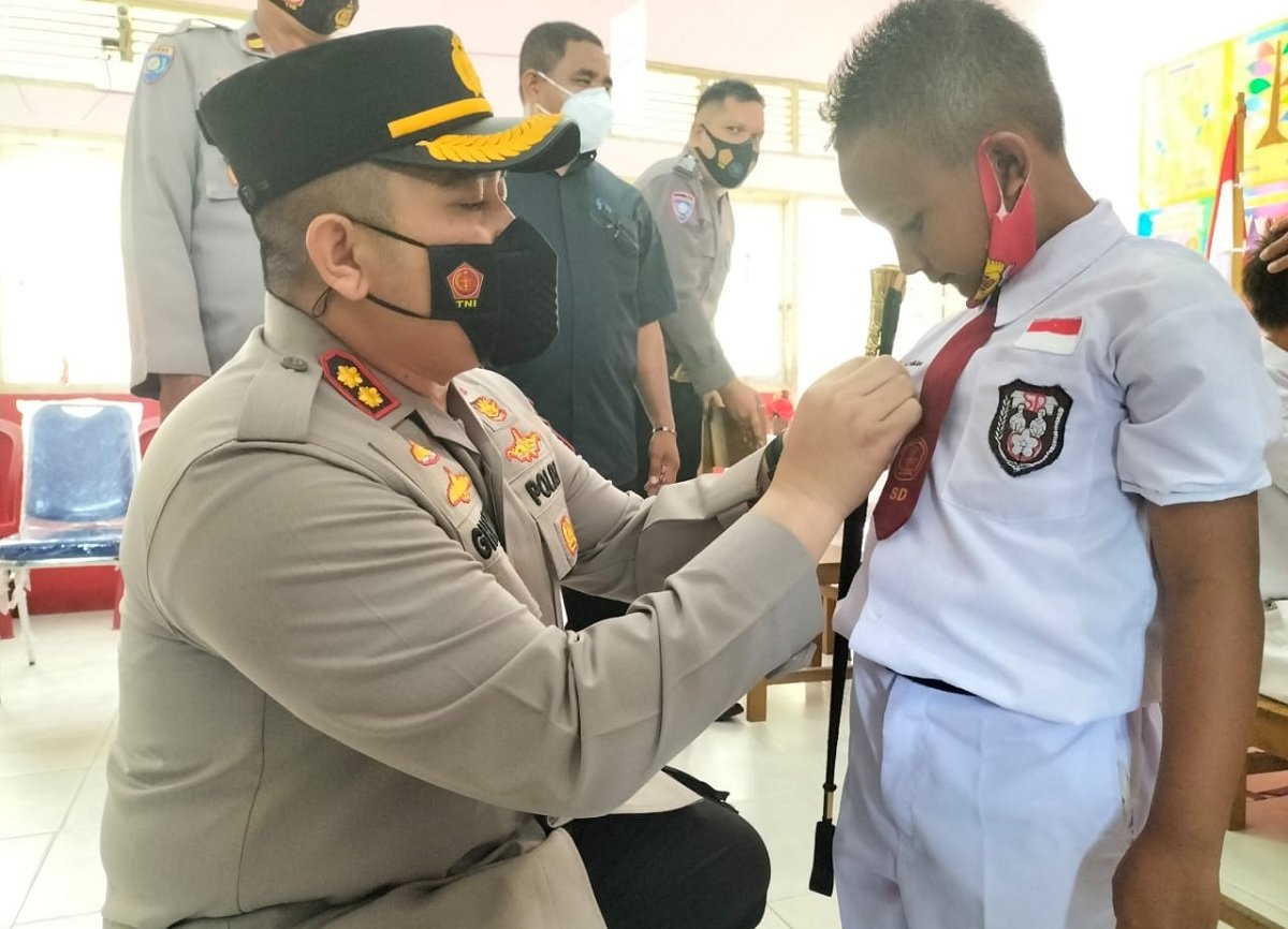 Kapolres Maluku Tengah AKBP Abdul Ghafur, S.I.K., S.H., M.Si. melakukan pemasangan pin kepada salah seorang anak di SD Naskat Yos Sudarso 1, usai melakukan vaksinasi, Senin (14/2/2022) (Foto : beritabeta.com)