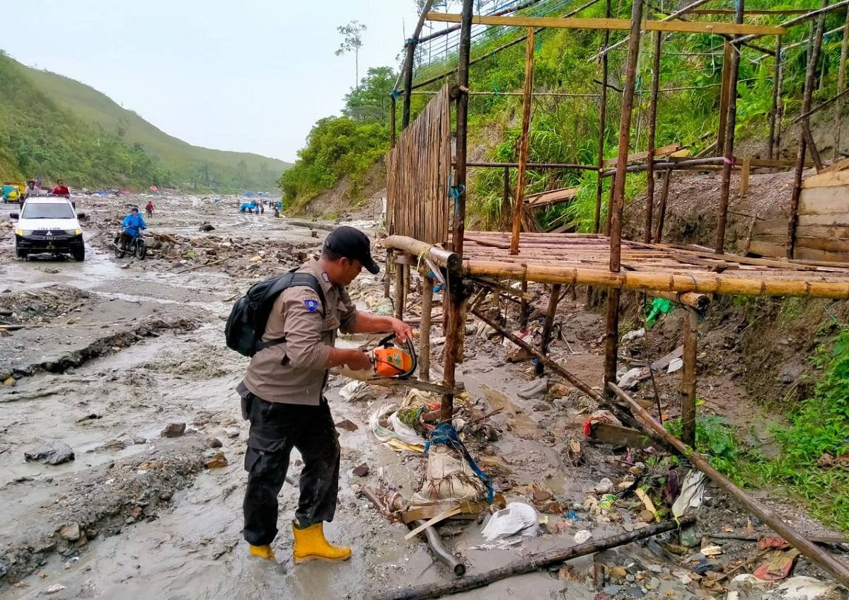 Seorang polisi anggota tim penertiban tambang emas ilegal di Gunung Botak memotong kayu peyangga tenda yang dibuat PETI di kawasan Sungai Anahoni (Foto : Humas Polres Pulau Buru)