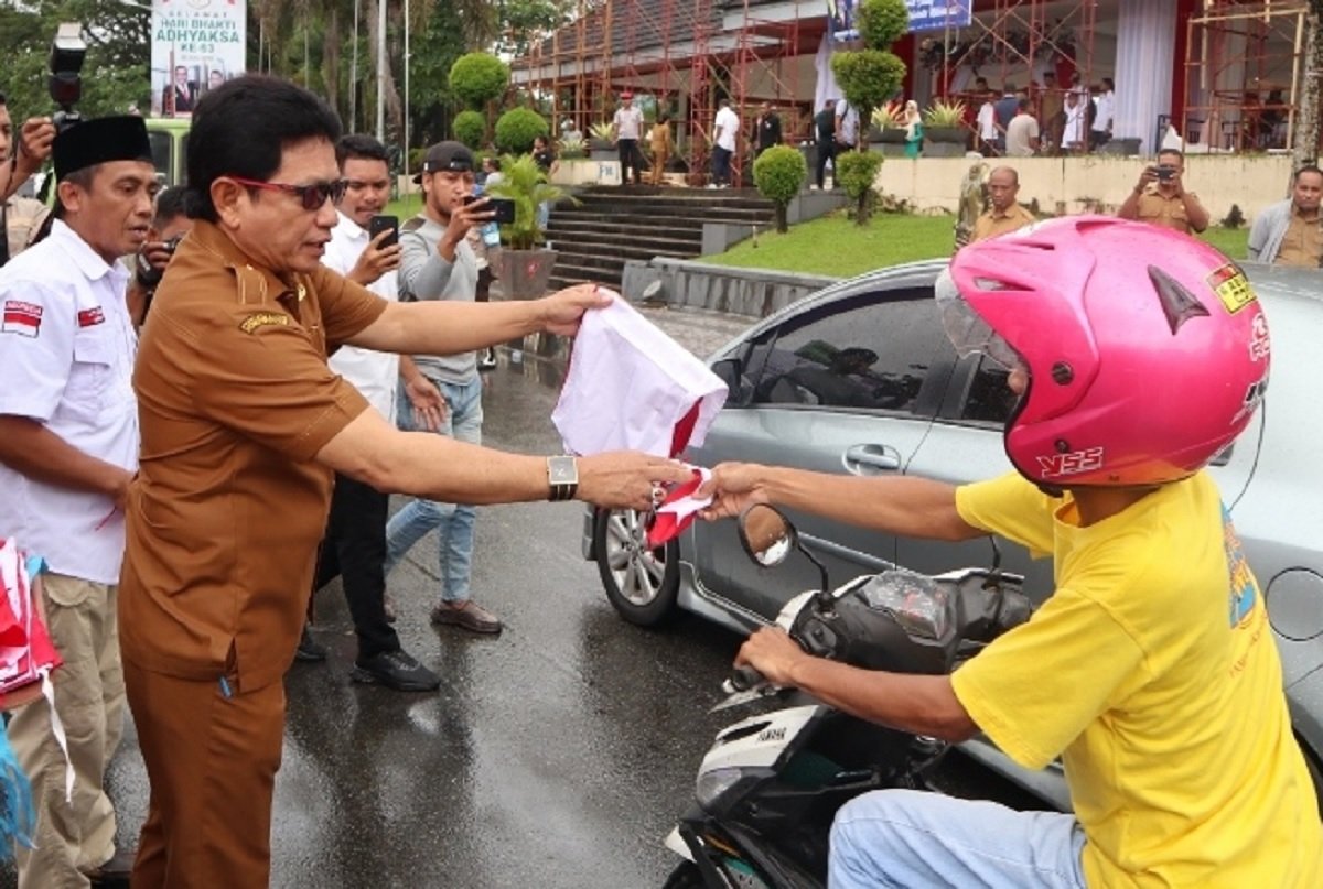 Sekretaris Daerah (Sekda) Maluku Sadali Ie membagikan bendera Merah Putih kepada pengendara roda dua di Kota Ambon dalam kegiatan pencanangan membagikan ribuan bendera Merah Putih kepada warga menyambut HUT Republik Indonesia ke-78 tahun (Foto : Istimewa)